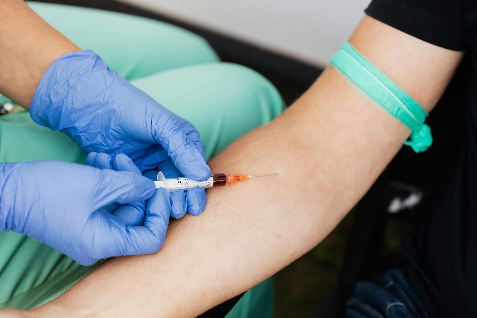 Gloved healthcare worker drawing blood from a patient’s arm with a syringe