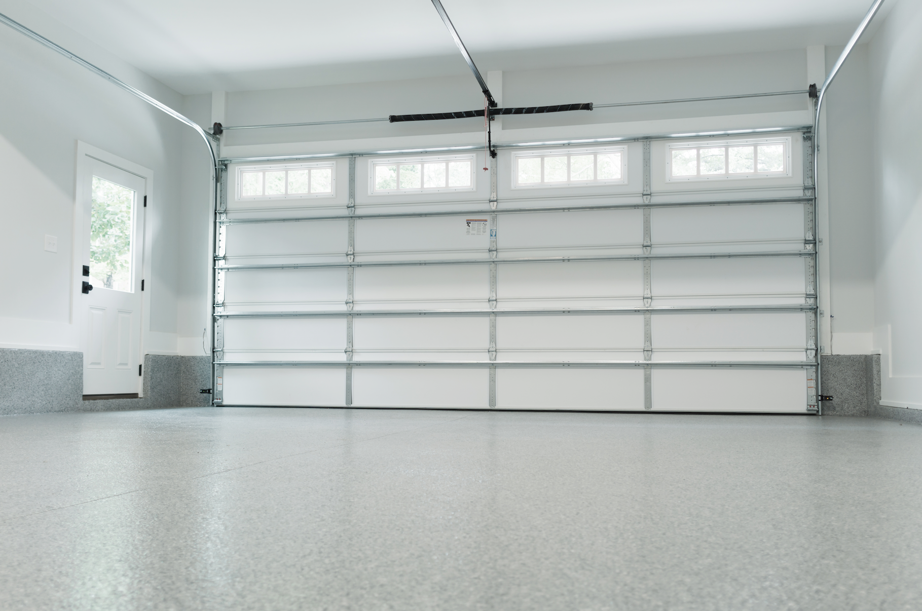 An empty garage with a white garage door open