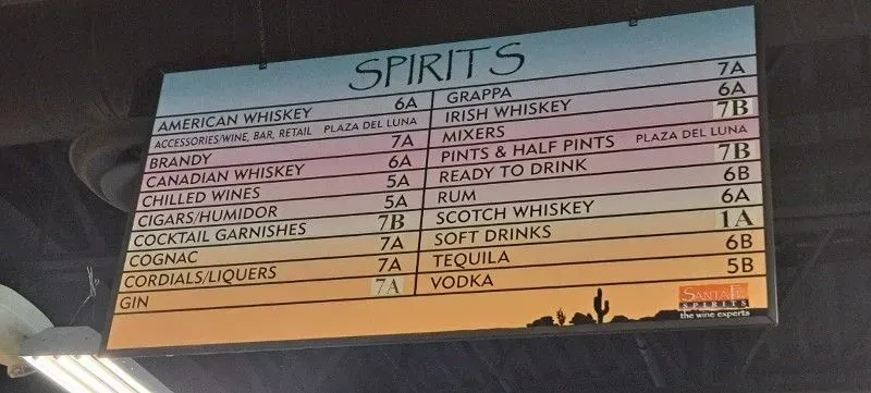 Bar menu titled “Spirits” listing drinks and prices on a sunset-themed board.