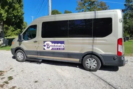 A tan work van parked on a gravel lot featuring a 