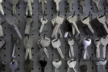 Rows of various metal keys hanging on a dark gray pegboard display.
