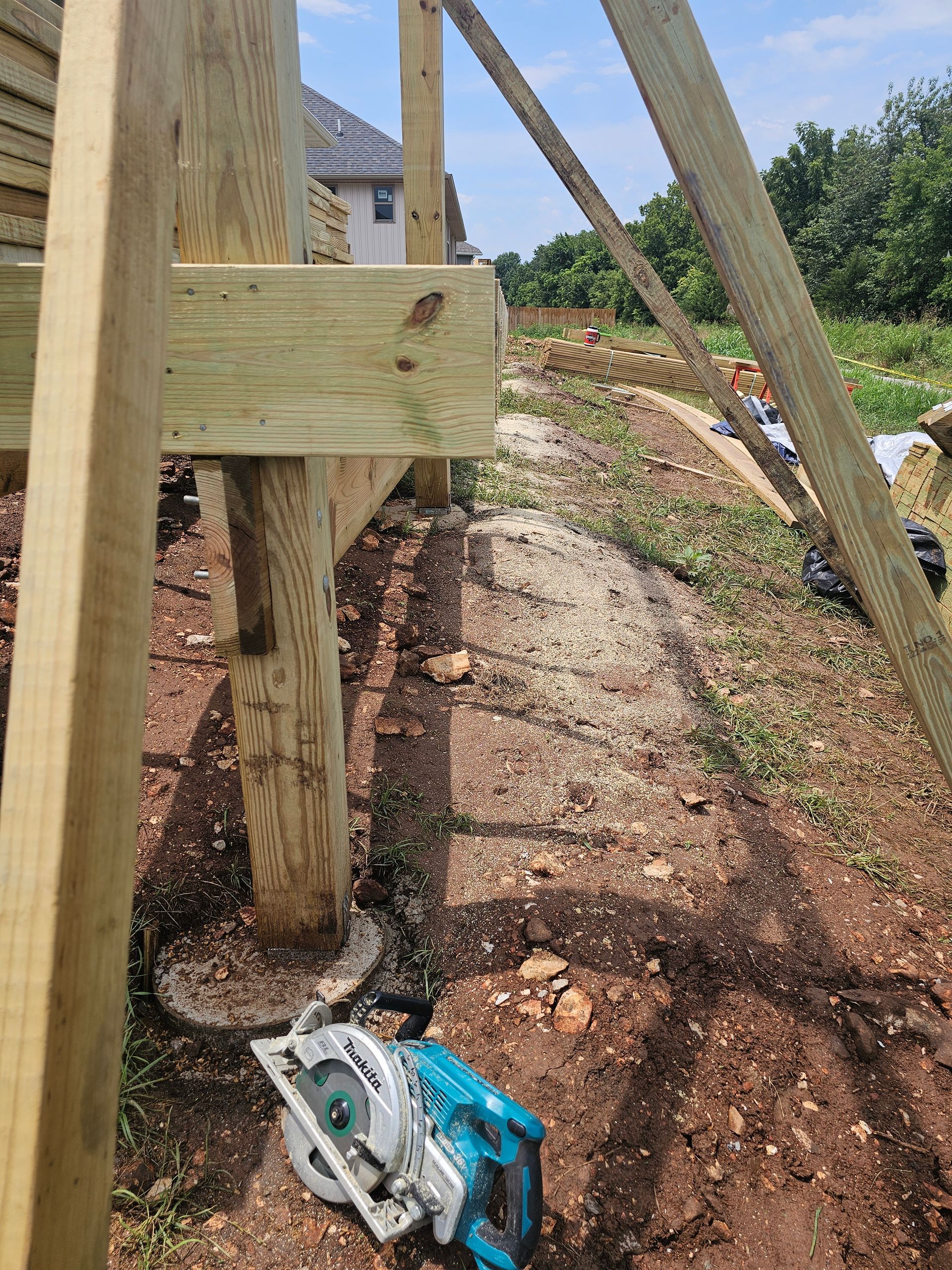 Wooden deck construction site with a circular saw on the ground.