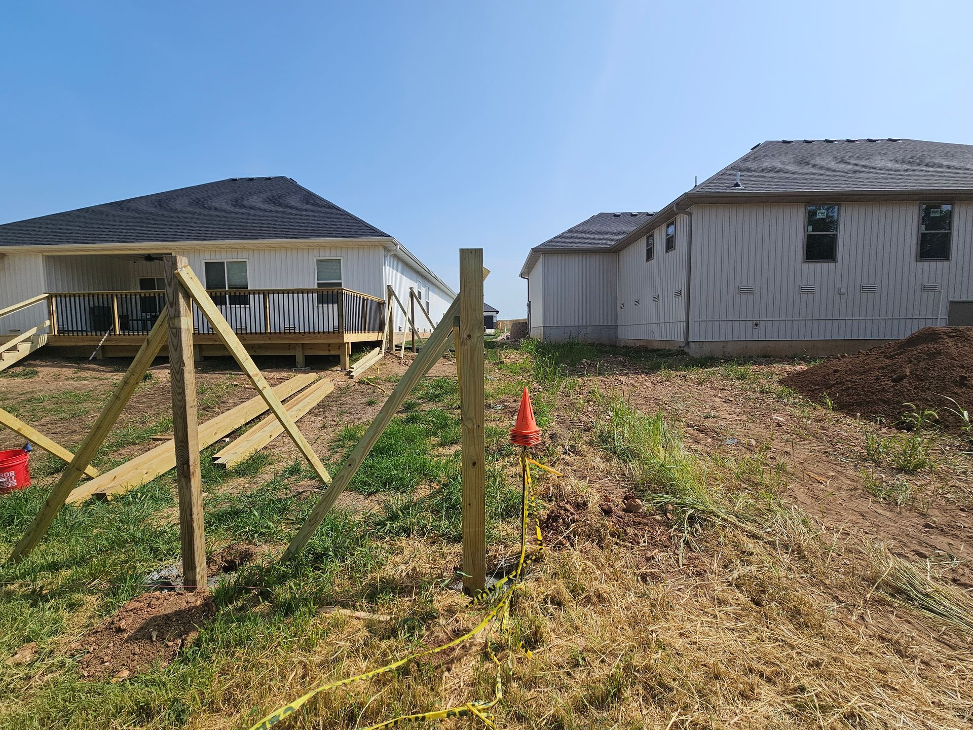 Wooden fence under construction between two houses on a sunny day.