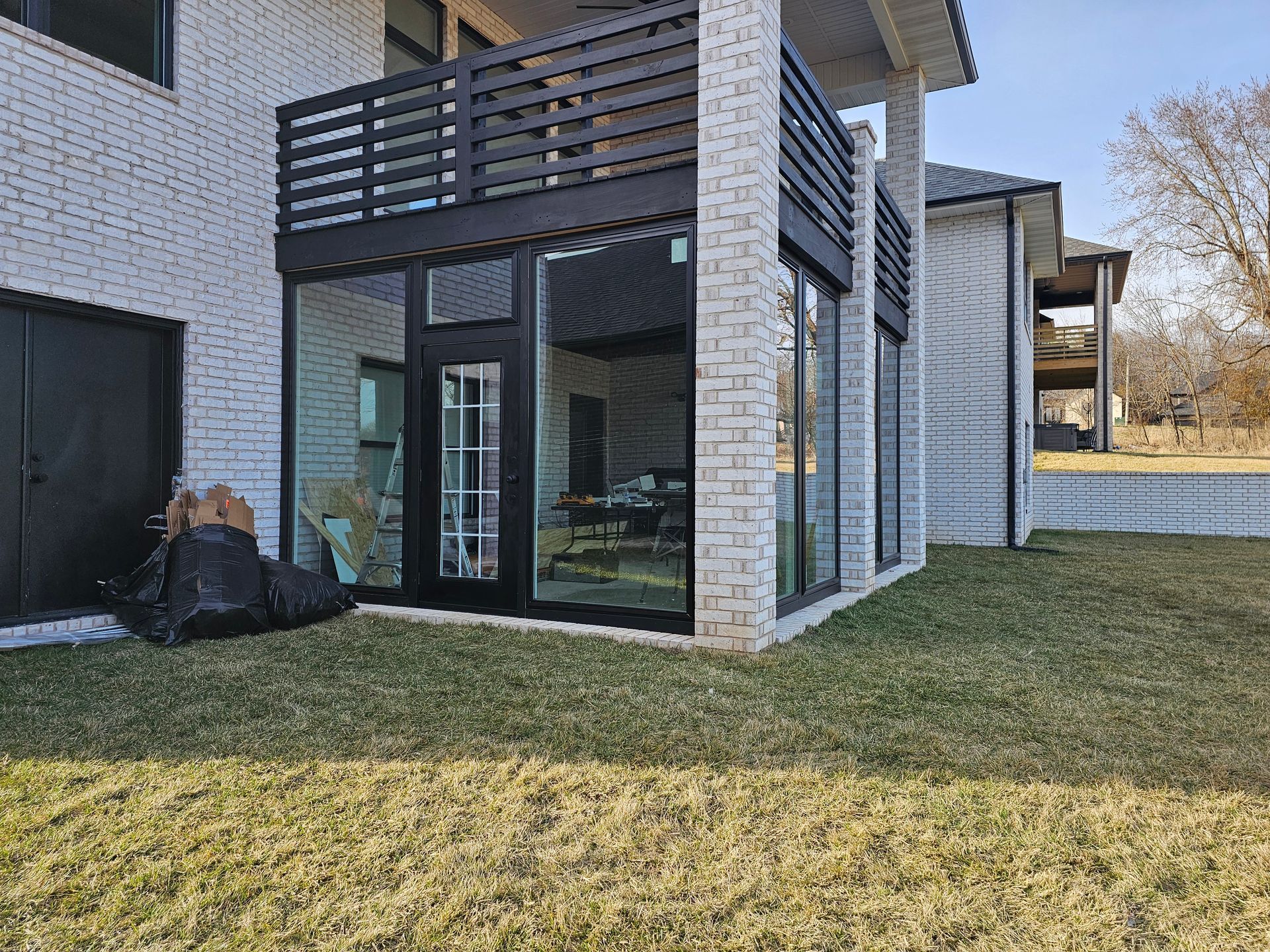 Exterior view of a modern brick house with large glass windows and a black balcony.