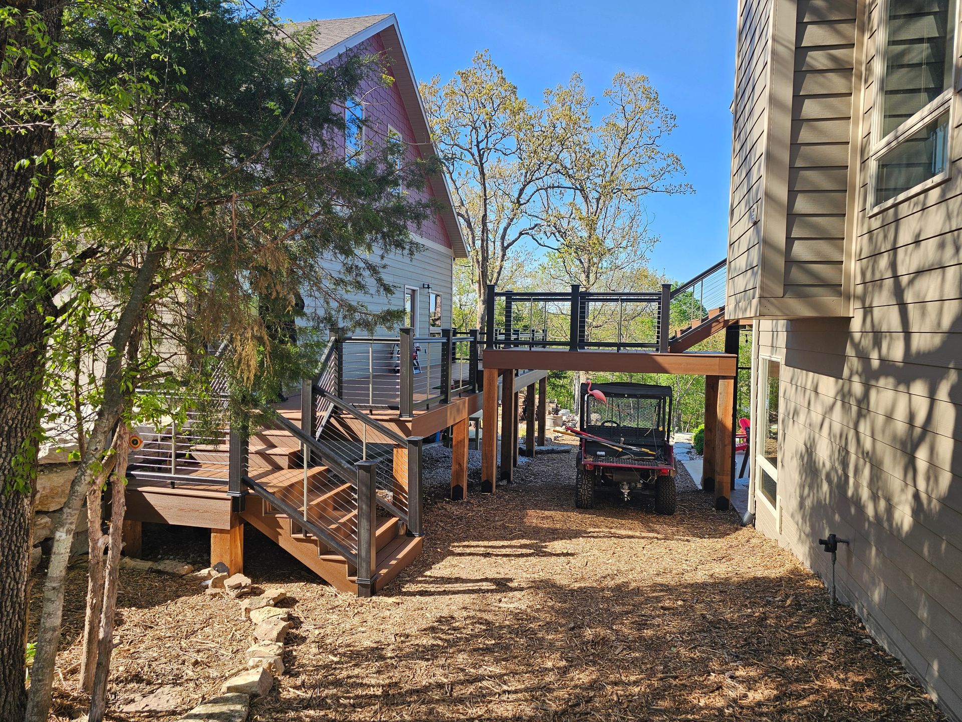 Backyard with multi-level wooden decks and a small utility vehicle parked beneath one deck.