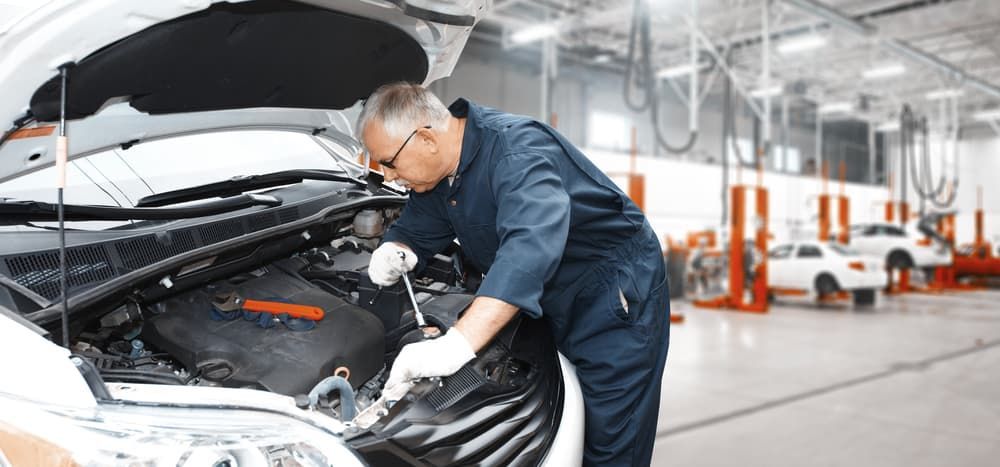 A Mechanic is Working on the Engine of a Car in a Garage — Coffs Auto Service in North Boambee Valley, NSW