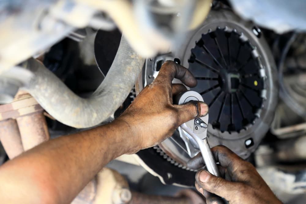 A Man is Working on a Car Clutch With a Wrench — Coffs Auto Service in North Boambee Valley, NSW