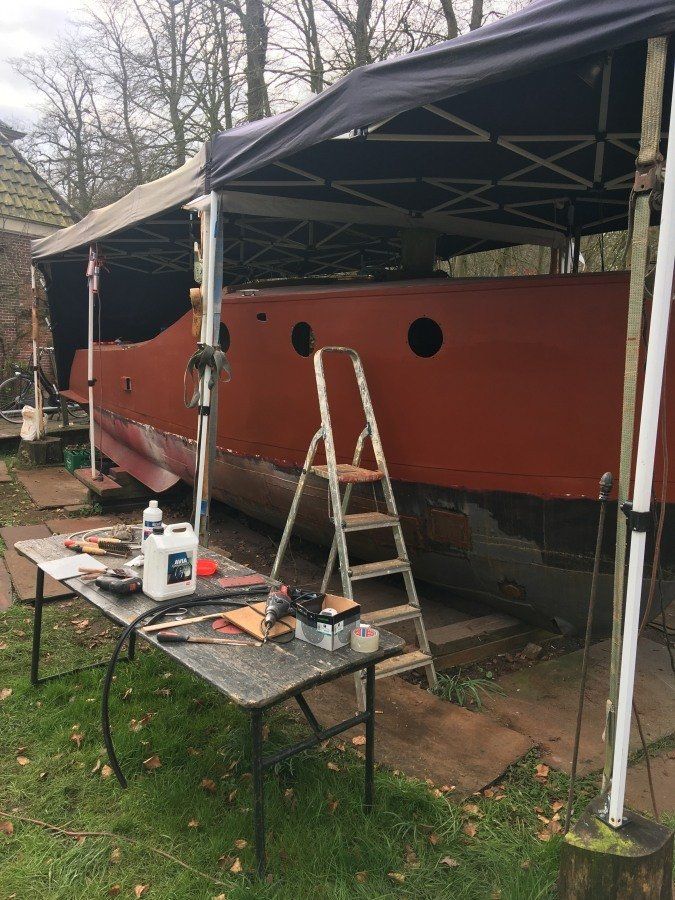 worktable and steps next to a boat being restored in dry dock