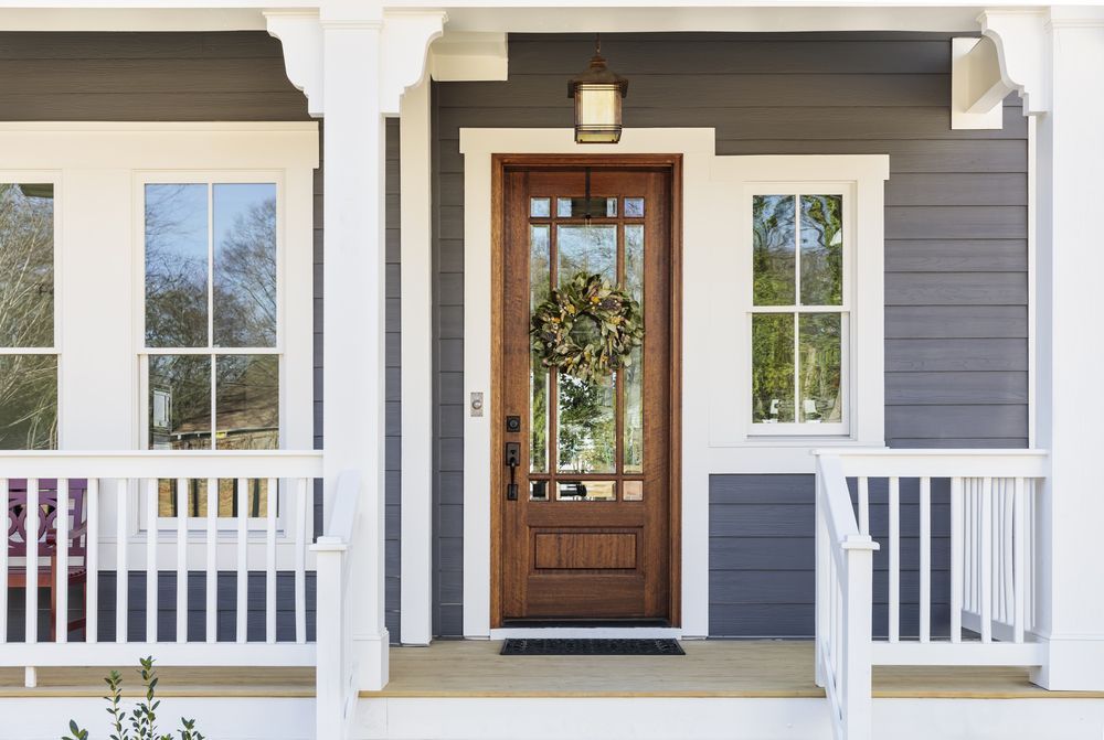 The front door of a house with a wreath on it and a porch.