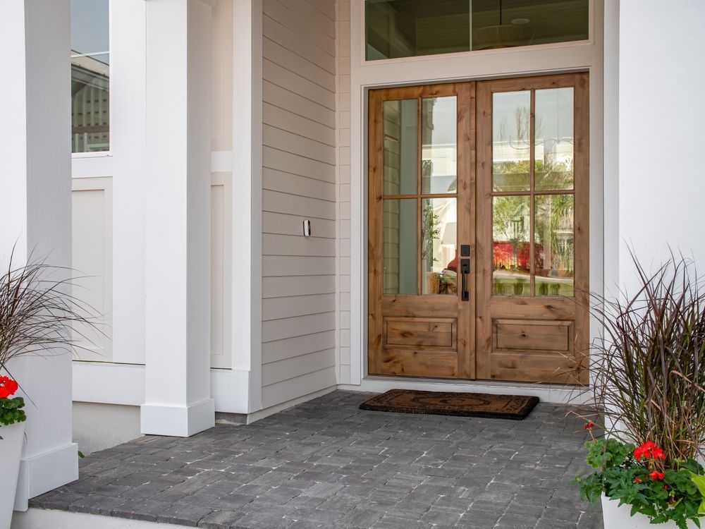 The front door of a house with a wooden door and a brick walkway.