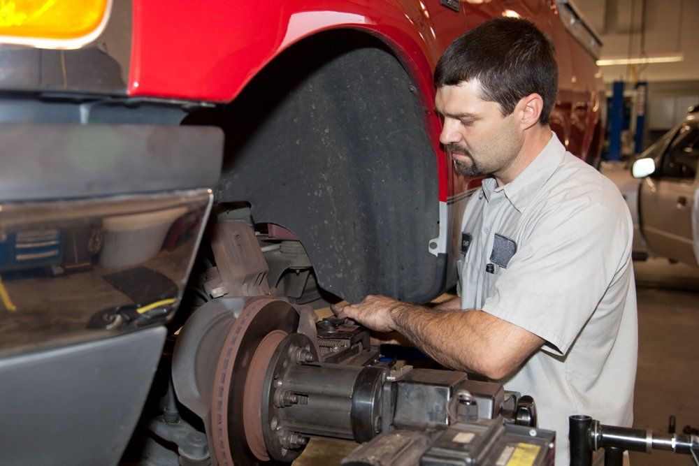 Truck Tire Being Repaired By Man — Almont, MI — Paul’s Collision and Towing Paul’s Truck Center