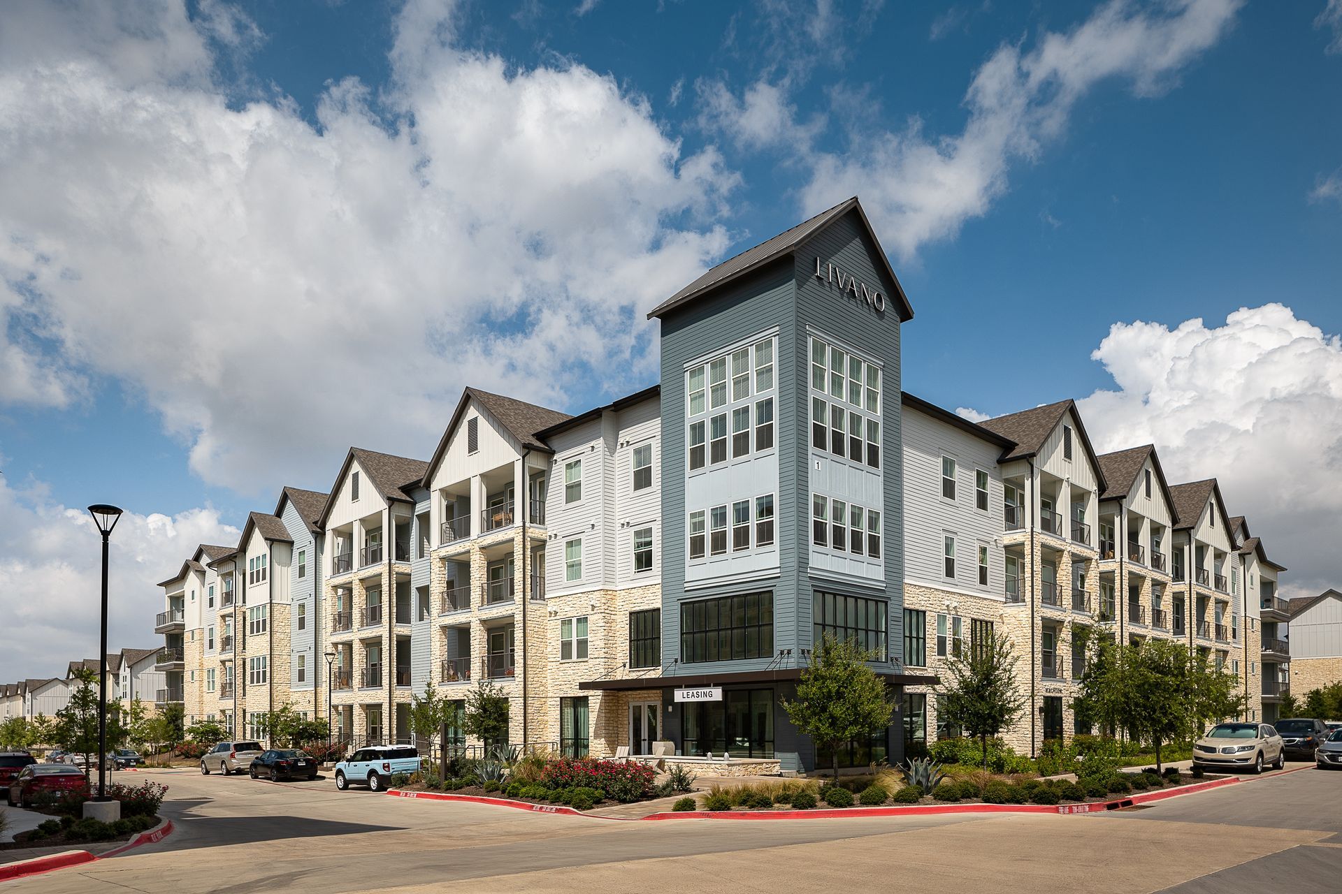 A large apartment building with a lot of windows and cars parked in front of it 