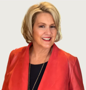 Blonde woman in red jacket smiles, gold necklace visible.