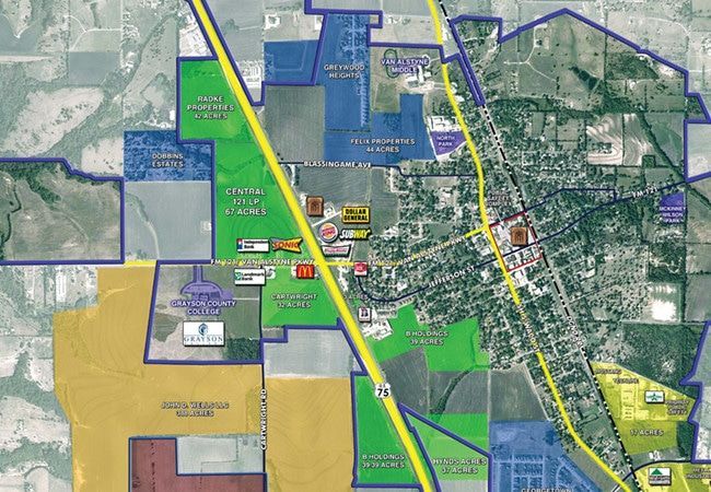 Aerial view map of a town with roads, buildings, and colored zoning areas. A highway runs vertically through the center.