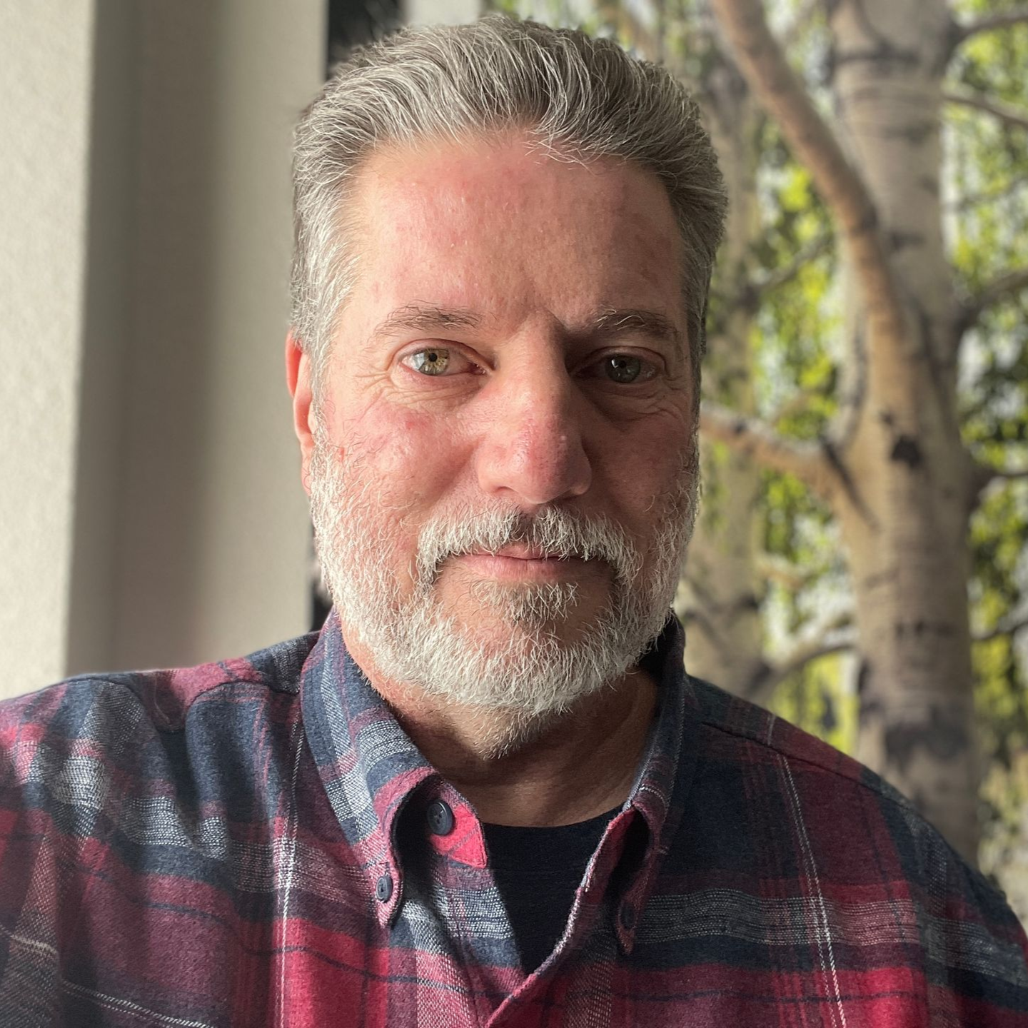 Smiling woman with shoulder-length blonde hair, wearing a light sweater over a teal shirt, against a plain background.