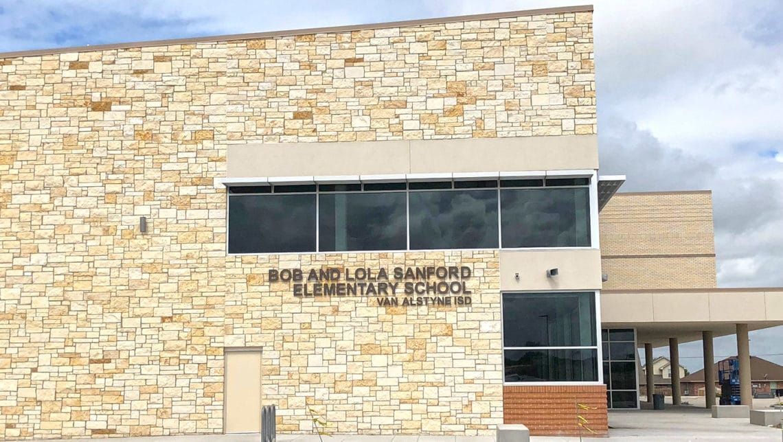 Bob and Lola Sanford Elementary School building exterior; beige stone facade, large windows, text on the wall.