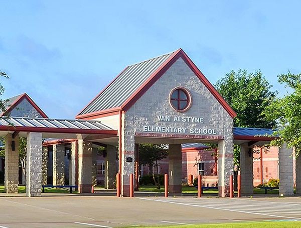 Van Alstyne Elementary School entrance with stone facade and red trim under a blue sky.