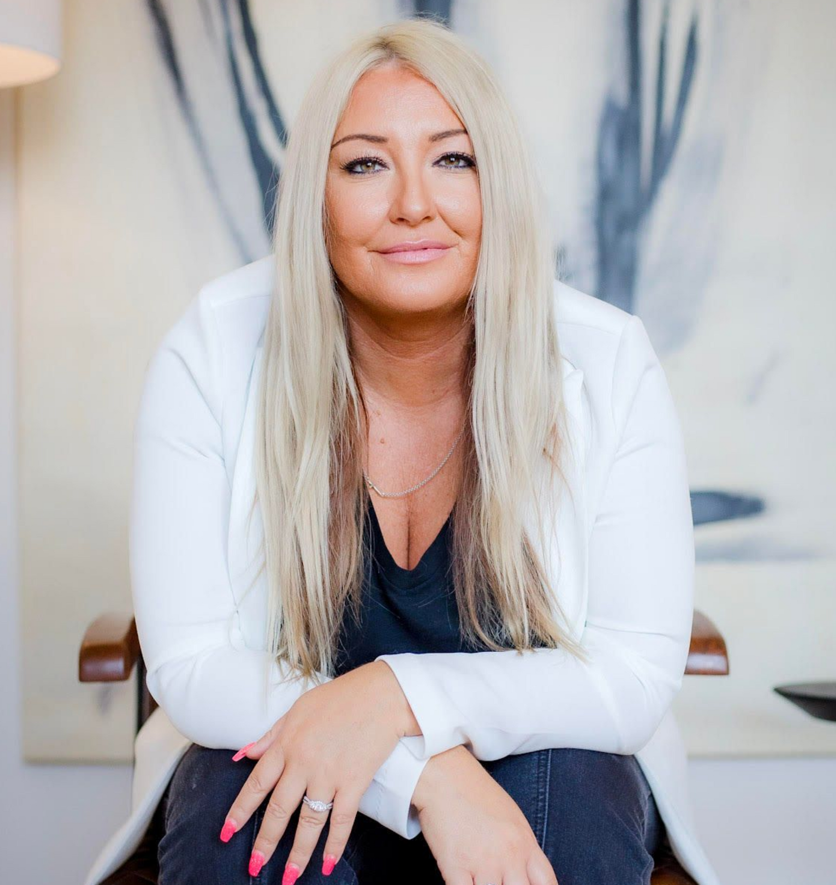 Man in a suit smiling, with a mustache and short dark hair, against a light gray background.