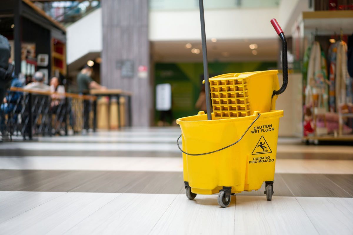 A yellow mop bucket is sitting on the floor in a mall
