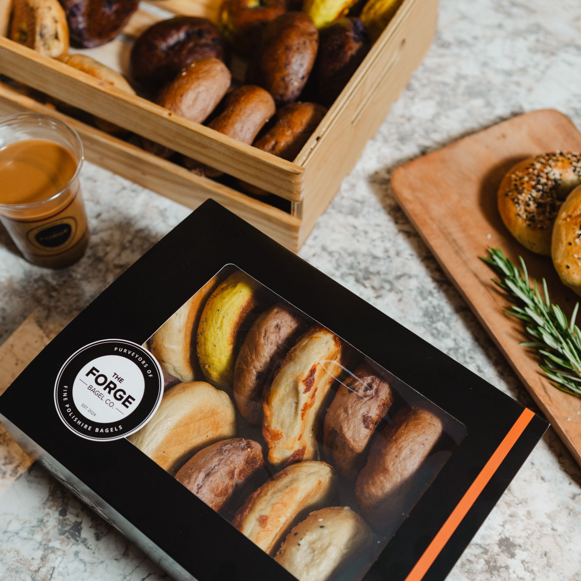 Boxes of The Forge Bagels and a coffee cup on a wooden surface, branded with