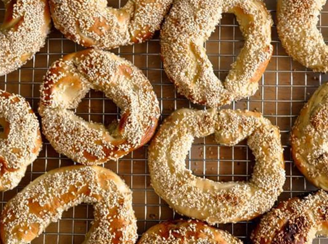 Rope style Bagels coated in sesame seeds, cooling on a wire rack.