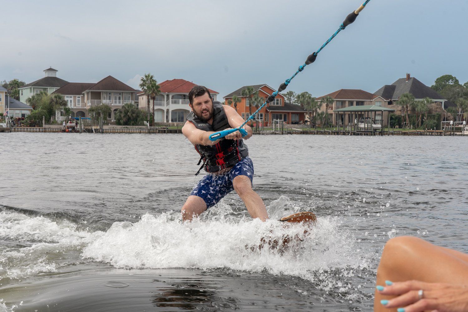 A man is water skiing on a lake while a woman watches.