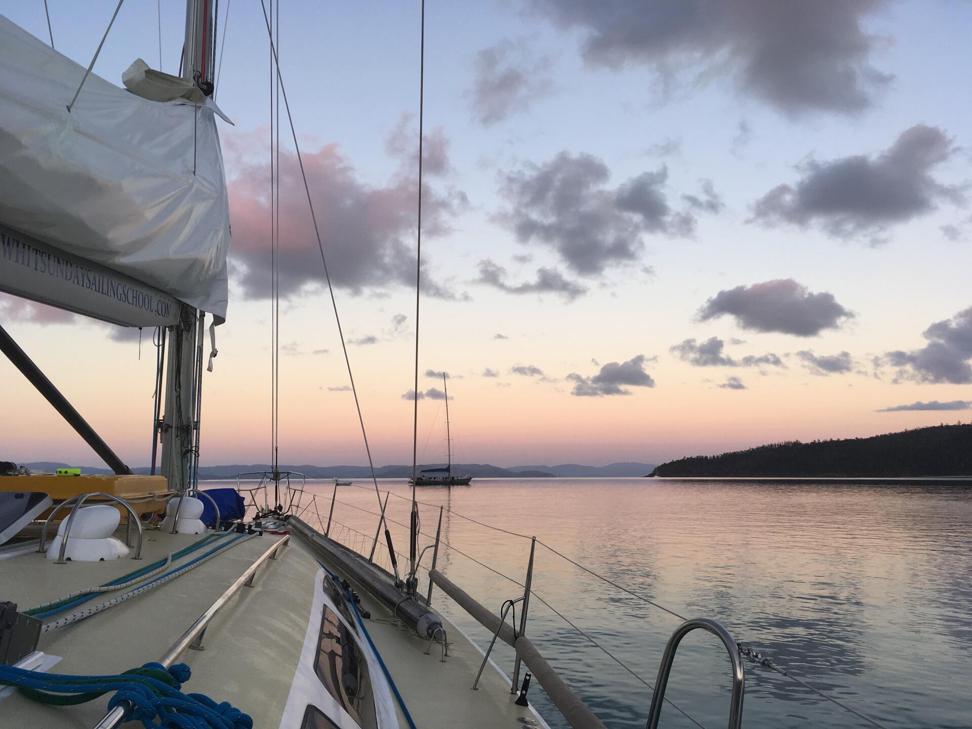 A sailboat in the water with a sunset in the background