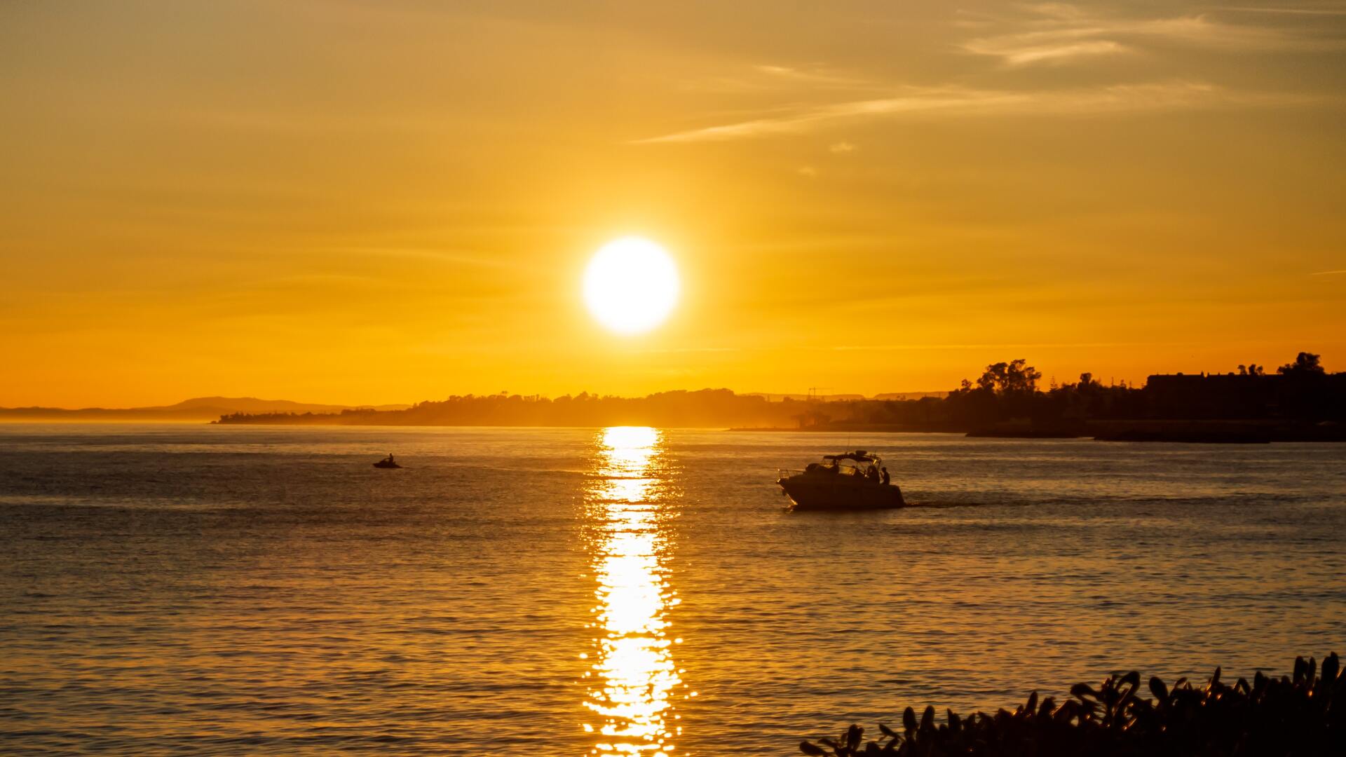 A boat is floating on top of a body of water at sunset.