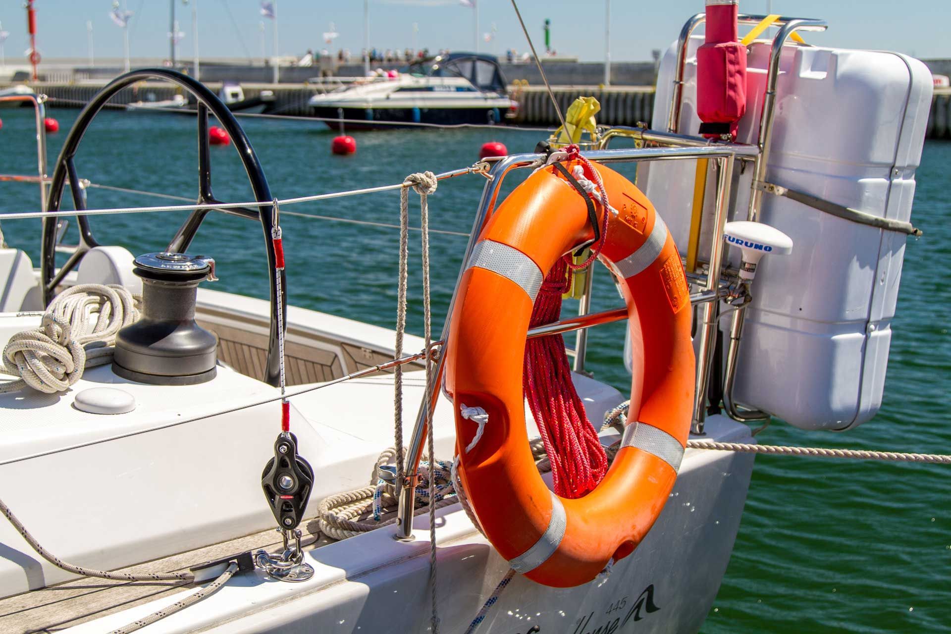 Orange life preserver and safety equipment on a sailboat at a marina.