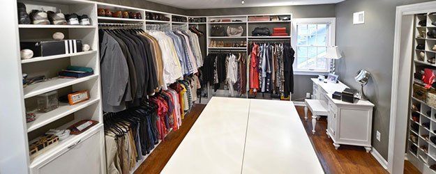 A large walk in closet filled with lots of clothes and shoes.