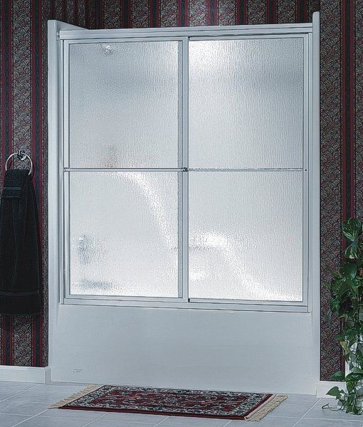 A bathtub with a sliding glass door and a rug on the floor