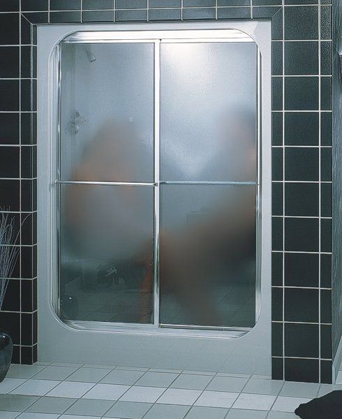 A person is taking a shower in a bathroom with a sliding glass door.