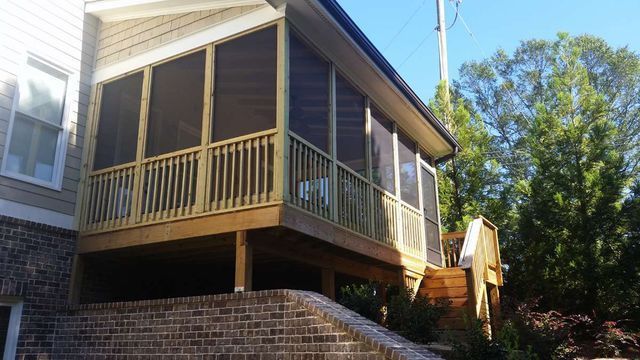 A screened in porch on the side of a house.