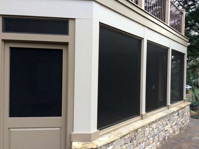 A house with a screened in porch and a stone wall.