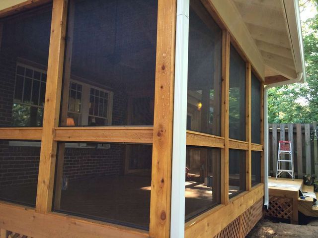 A screened in porch with a ladder in the background.