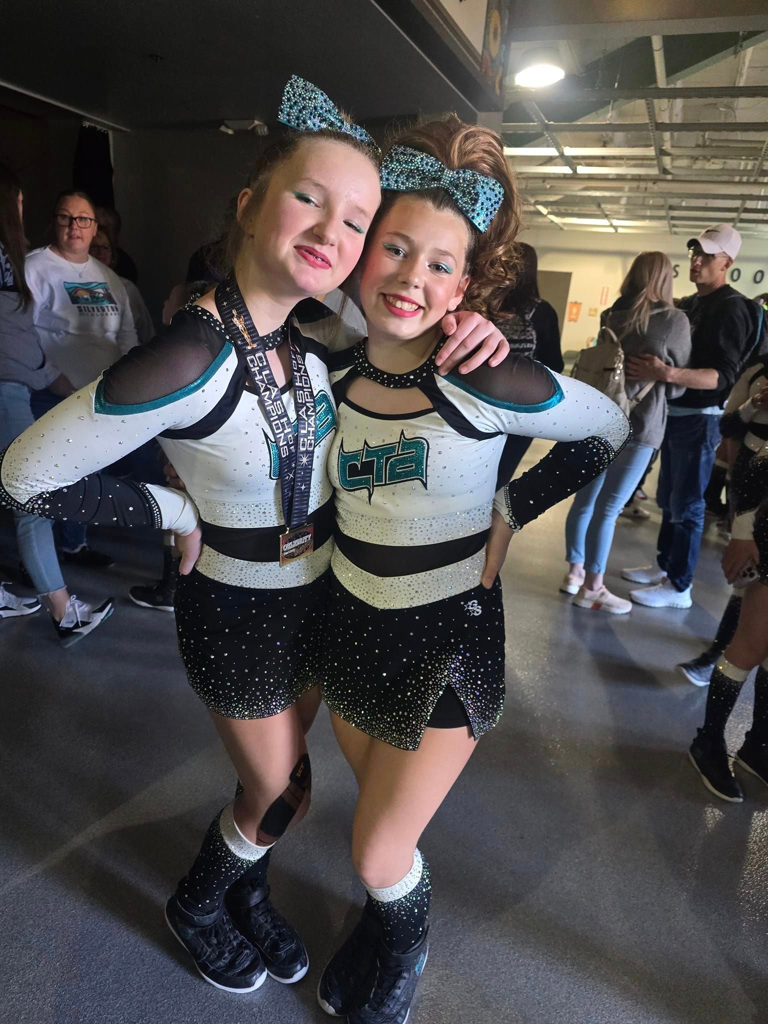 Two cheerleaders are posing for a picture together in a gym.