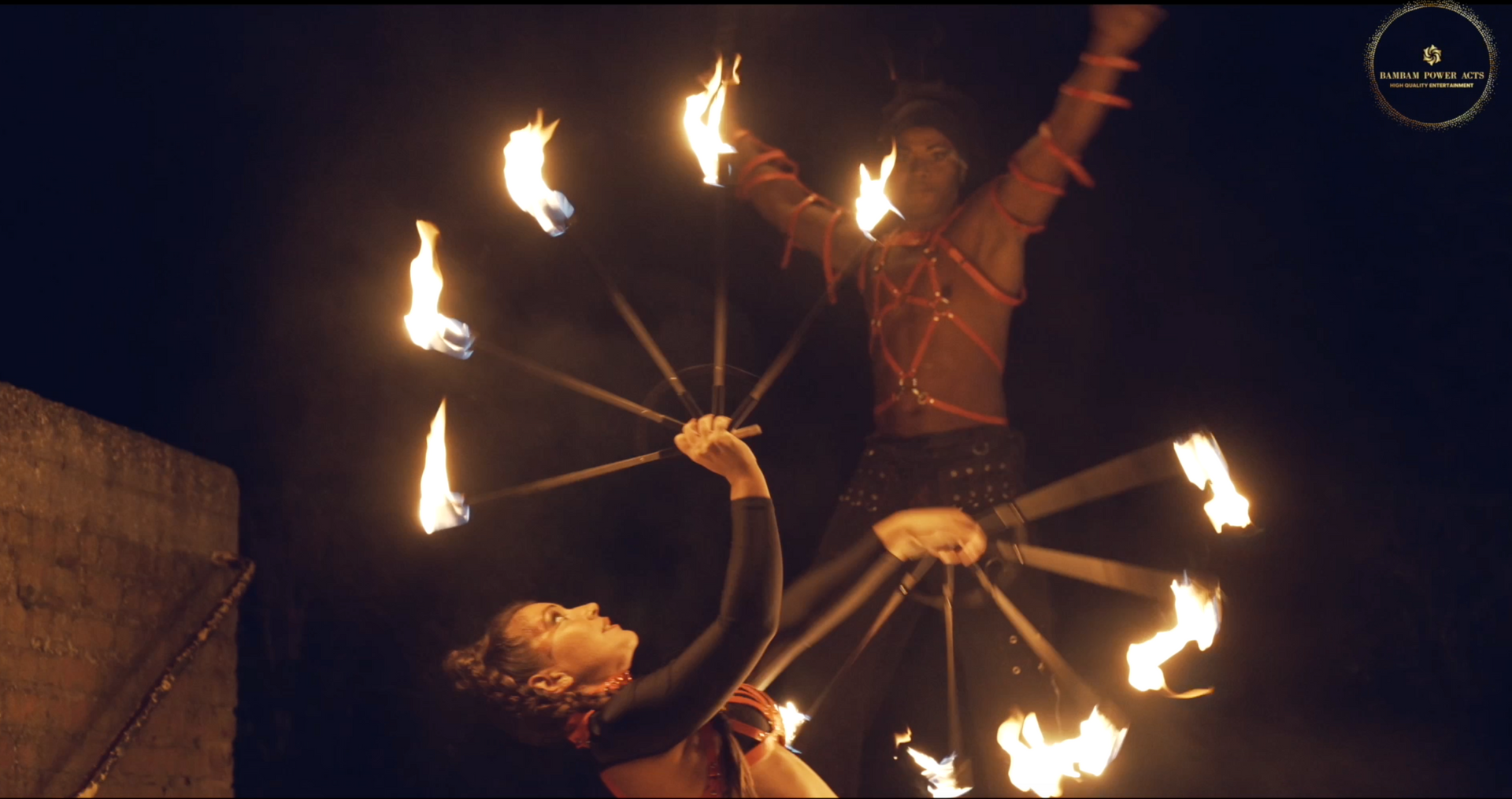 Two people performing fire dance at night with flaming props.