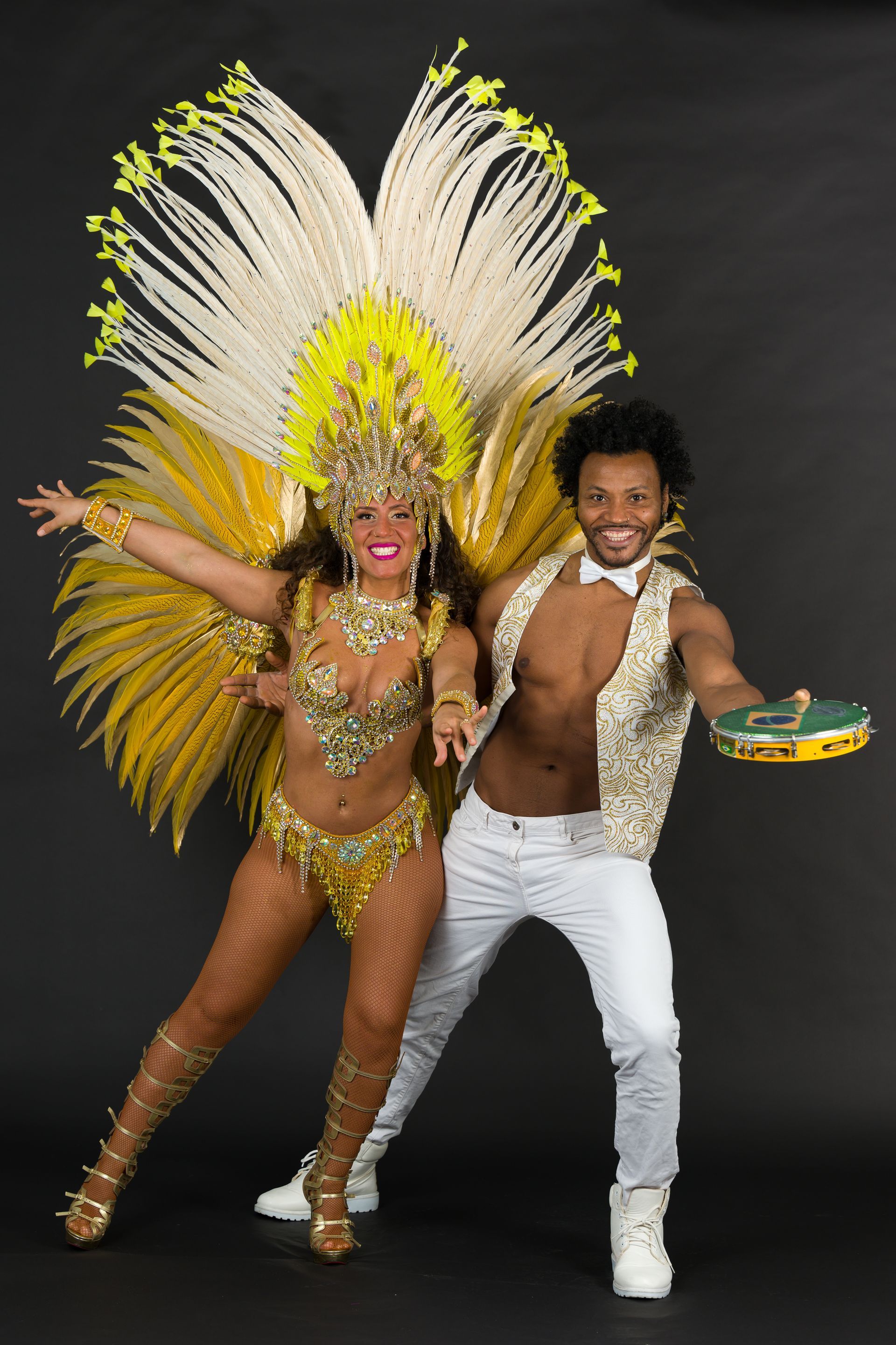 Couple in vibrant yellow costumes dancing, black background.