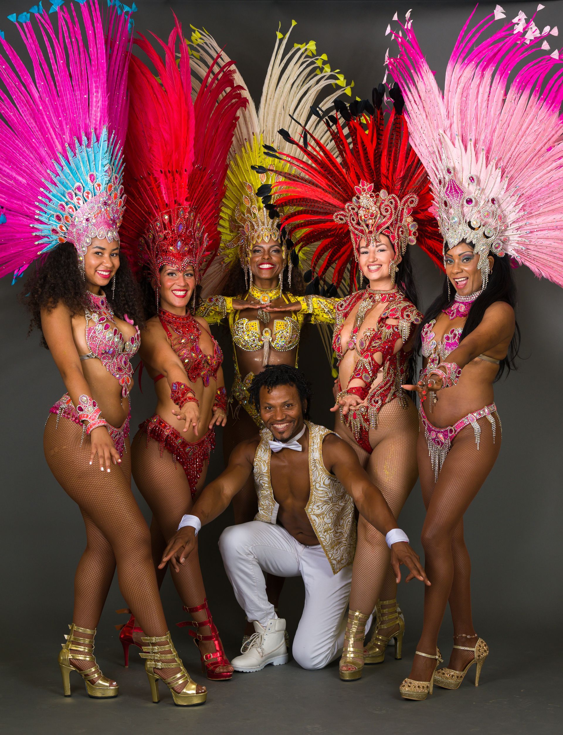 Group of dancers in vibrant costumes with elaborate headdresses posing for a photo.