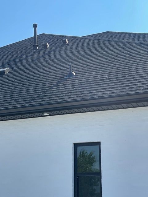 Person installing roofing shingles on a rooftop, using his hands.