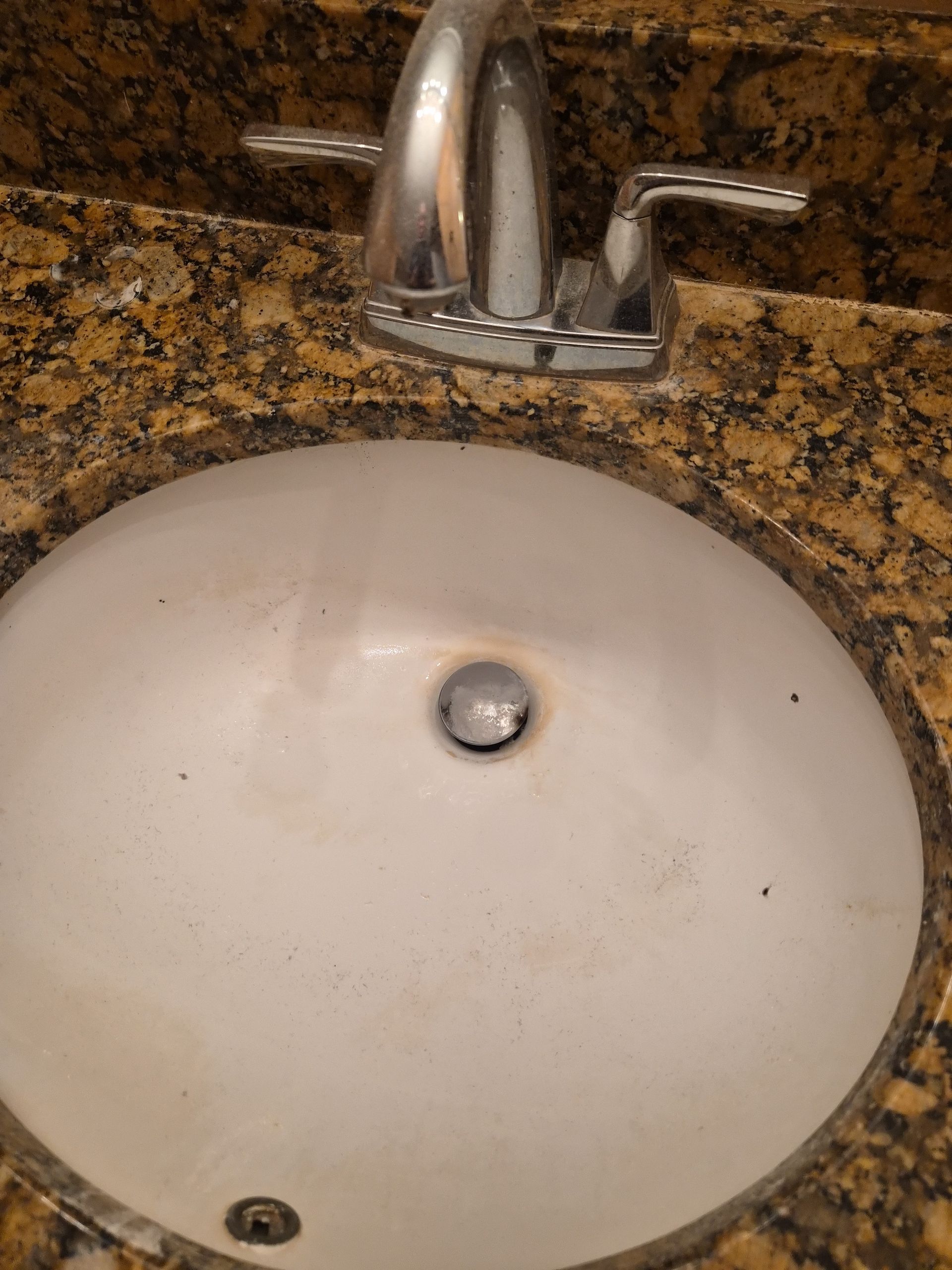 Open toilet in a small tiled bathroom stall with a trash can beside it