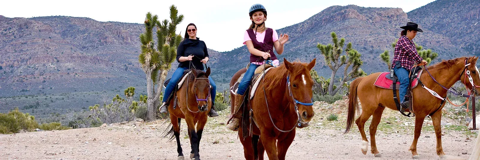 Three people are riding horses in the desert.