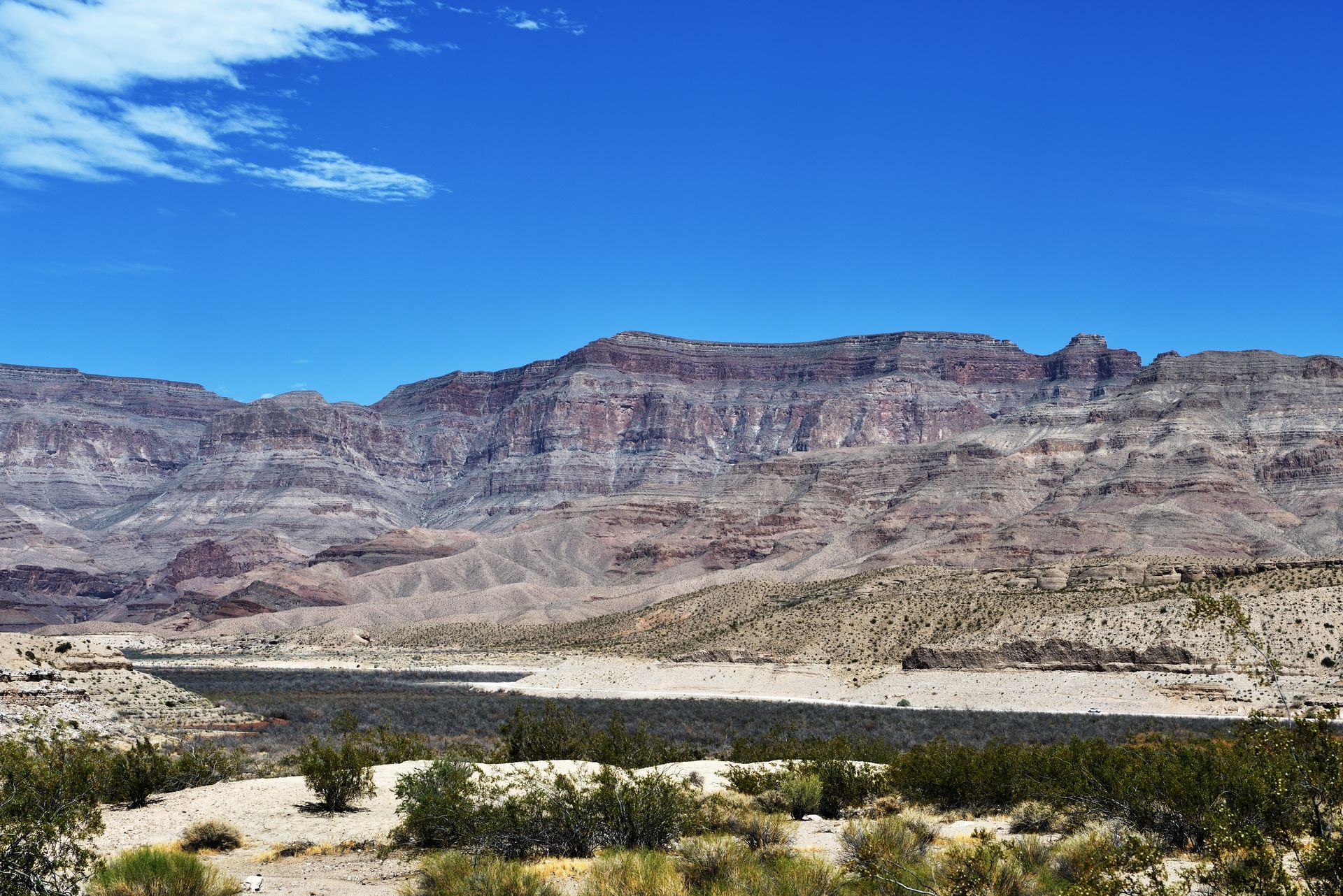 Mountains and desert landscape under a bright blue sky.