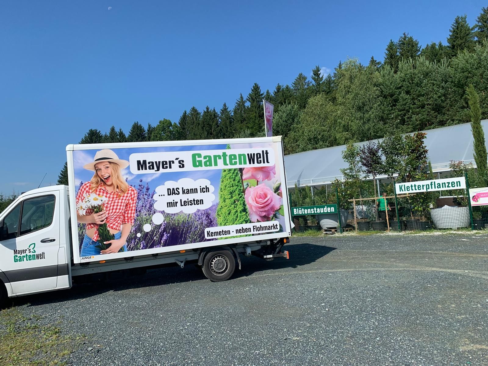 Tiki-Statue vor Bambuszaun umgeben von Pflanzen.