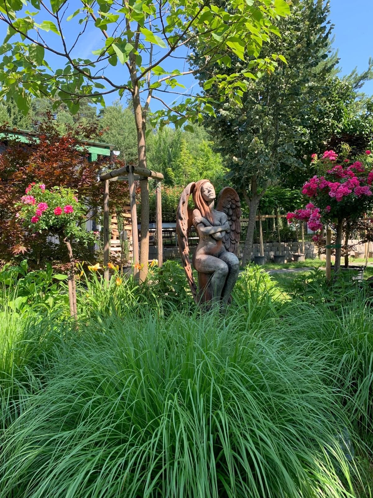 Eine Statue einer Frau, die auf einer Bank in einem Garten sitzt.