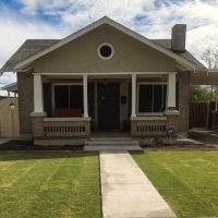 A small brick house with a porch and a walkway leading to it.