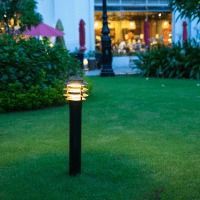 A lamp post is sitting in the middle of a lush green lawn.