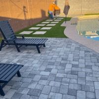 A man is cleaning a patio next to a swimming pool.