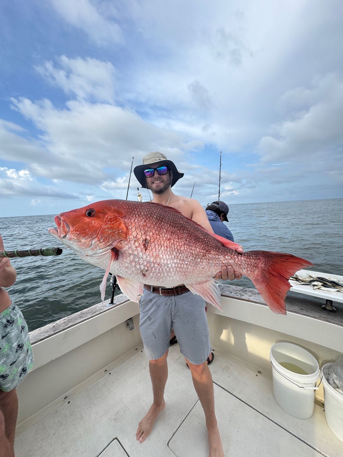 Person on a boat holding a large red fish on the open sea
