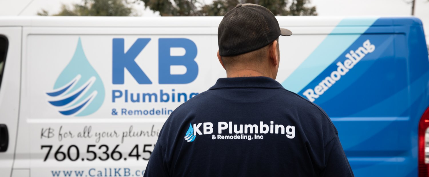 Man in a blue KB Plumbing shirt stands in front of a white van with the company logo.